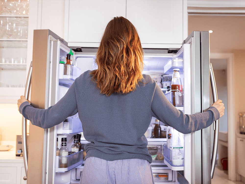 woman looking in a refrigerator for good cheese packaging